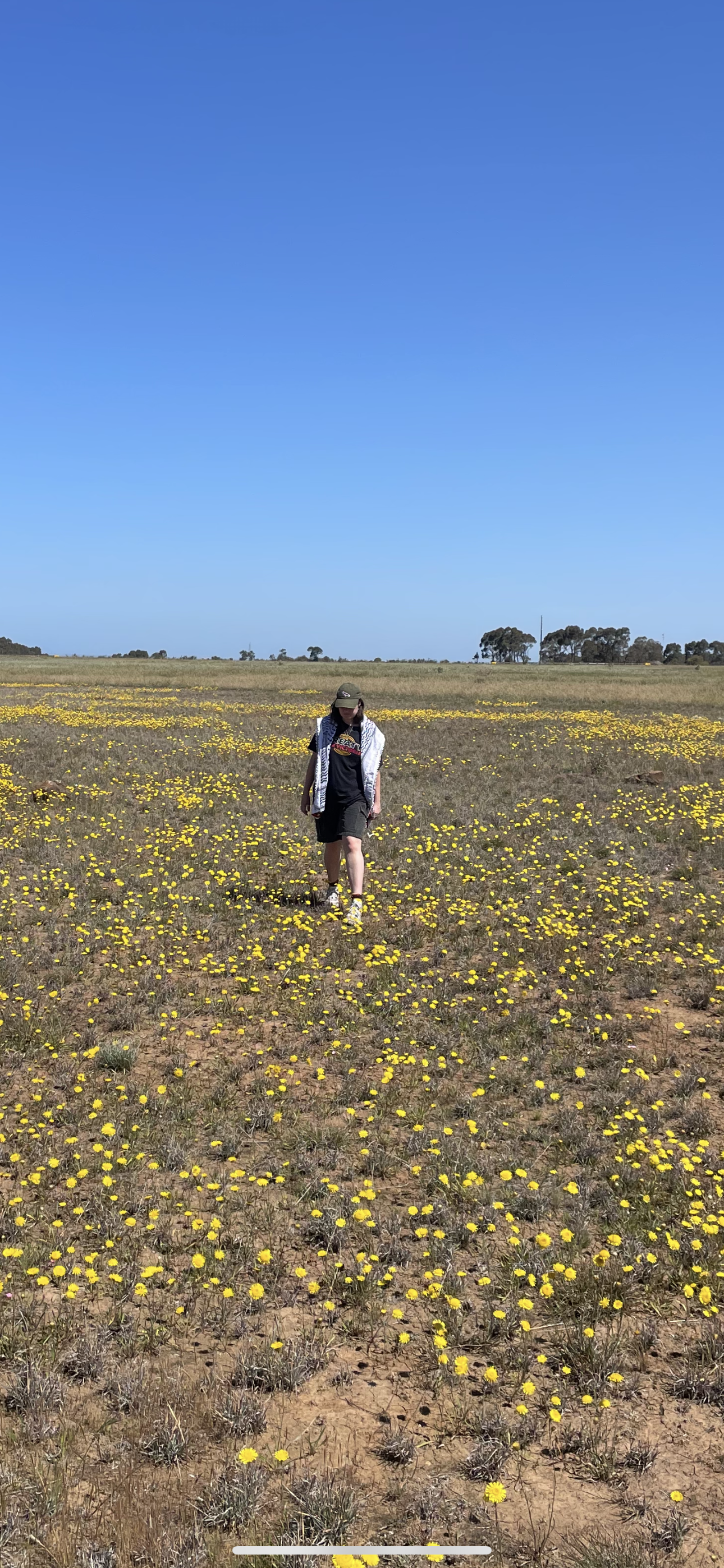 Brittney Henderson in a native grassland patch wearing a keffiyuh