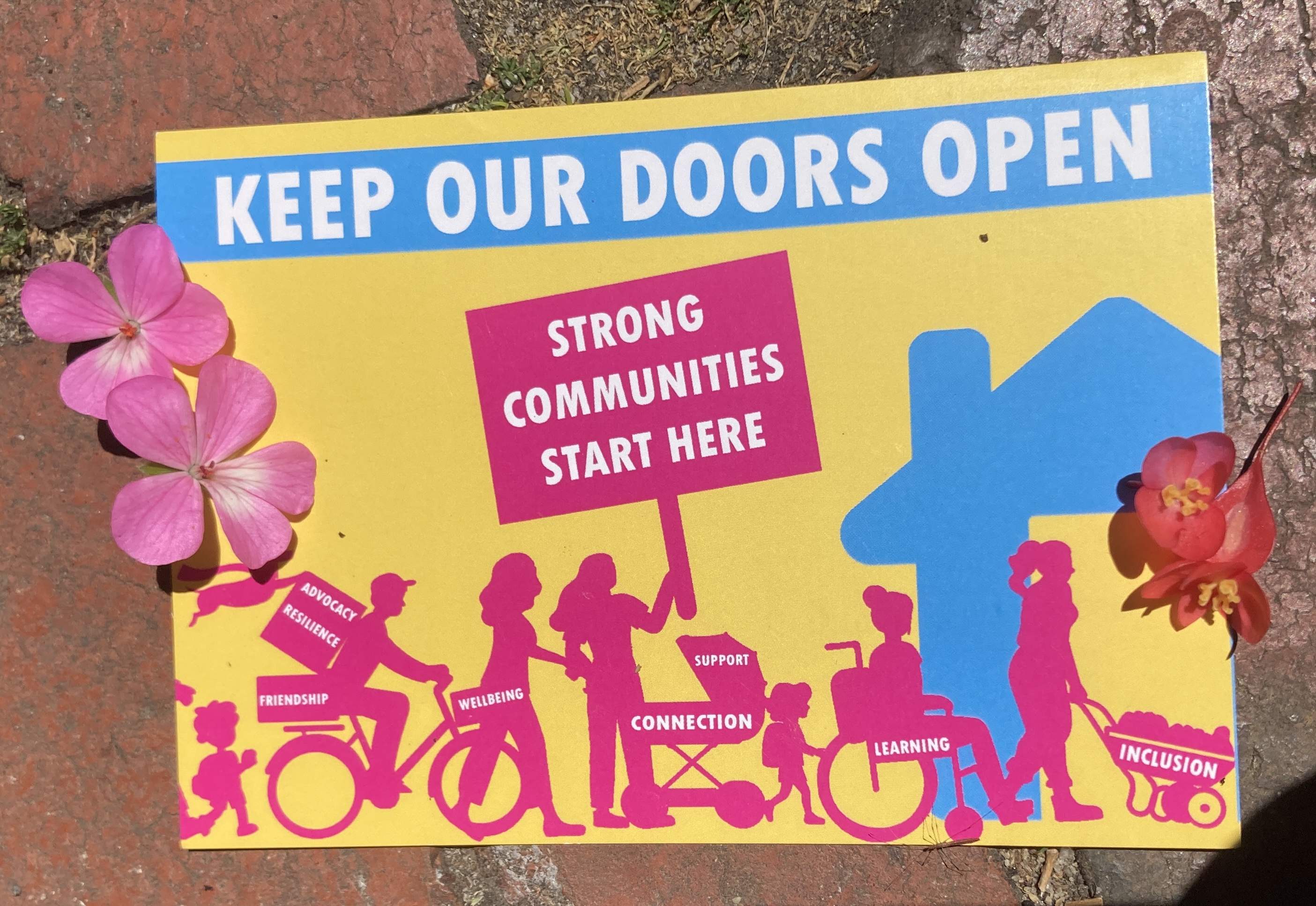 I mage of the post card mentioned in the interview. It features the words 'Keep Our Doors Open, Strong Communities Start Here." Includes image of a diverse looking community entering a neighbourhood house.