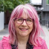 femme appearing person pink hair dark-rimmed glasses