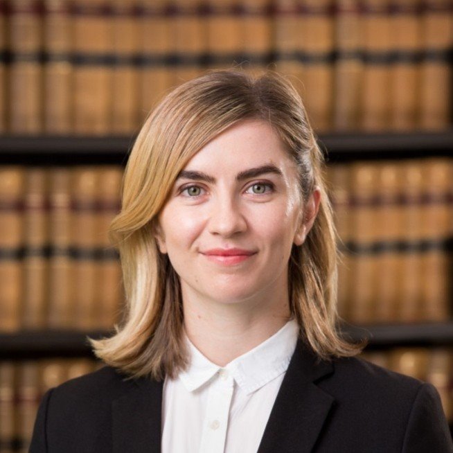 Nevena Spirovski law books in background, black  jacket, white blouse