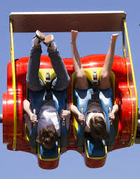 A couple of people hang upside down in a show ride