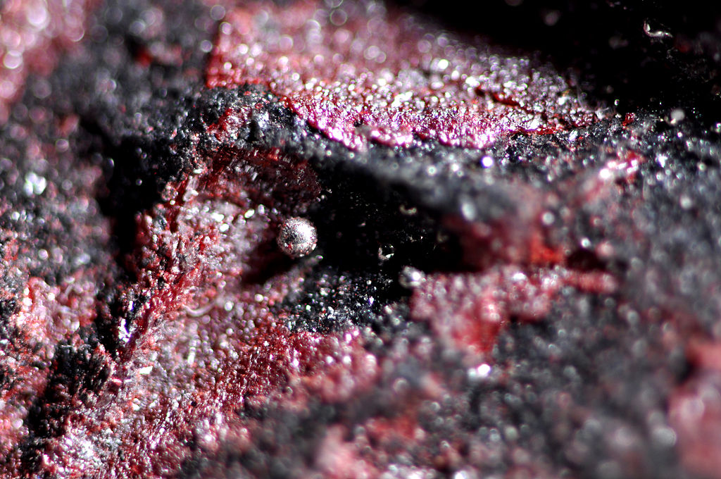 A drop of pure liquid mercury on cinnabar, an ore of mercury sulphide (photo by Parent Géry, via Wikimedia Commons)