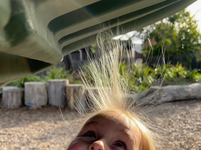 A child's hair standing up attracted to a plastic slide due to static electricity