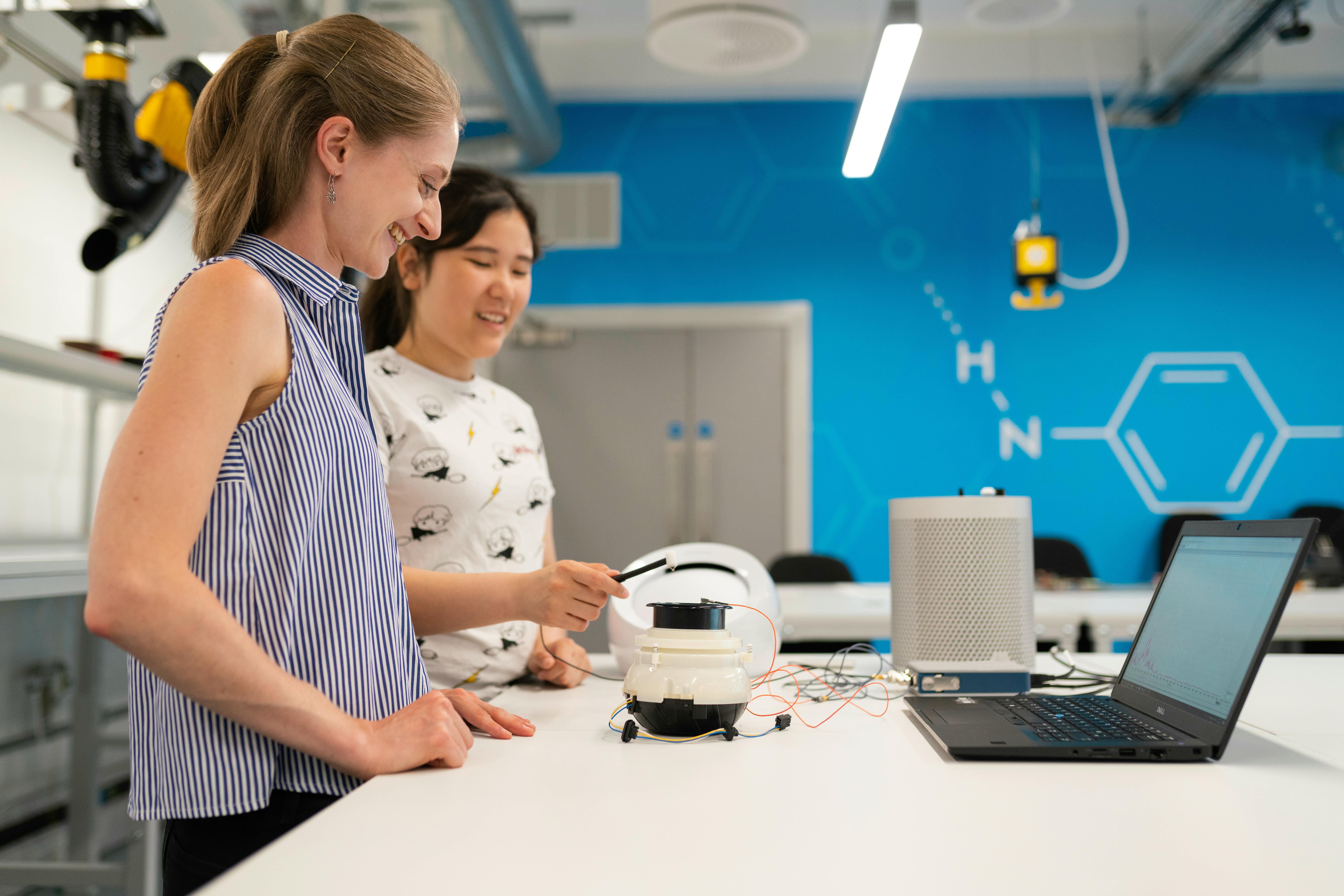 Two women working with tech on a white desk