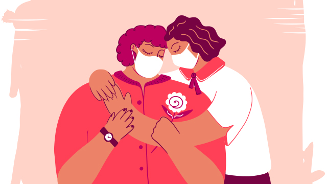 Two masked people share a hug