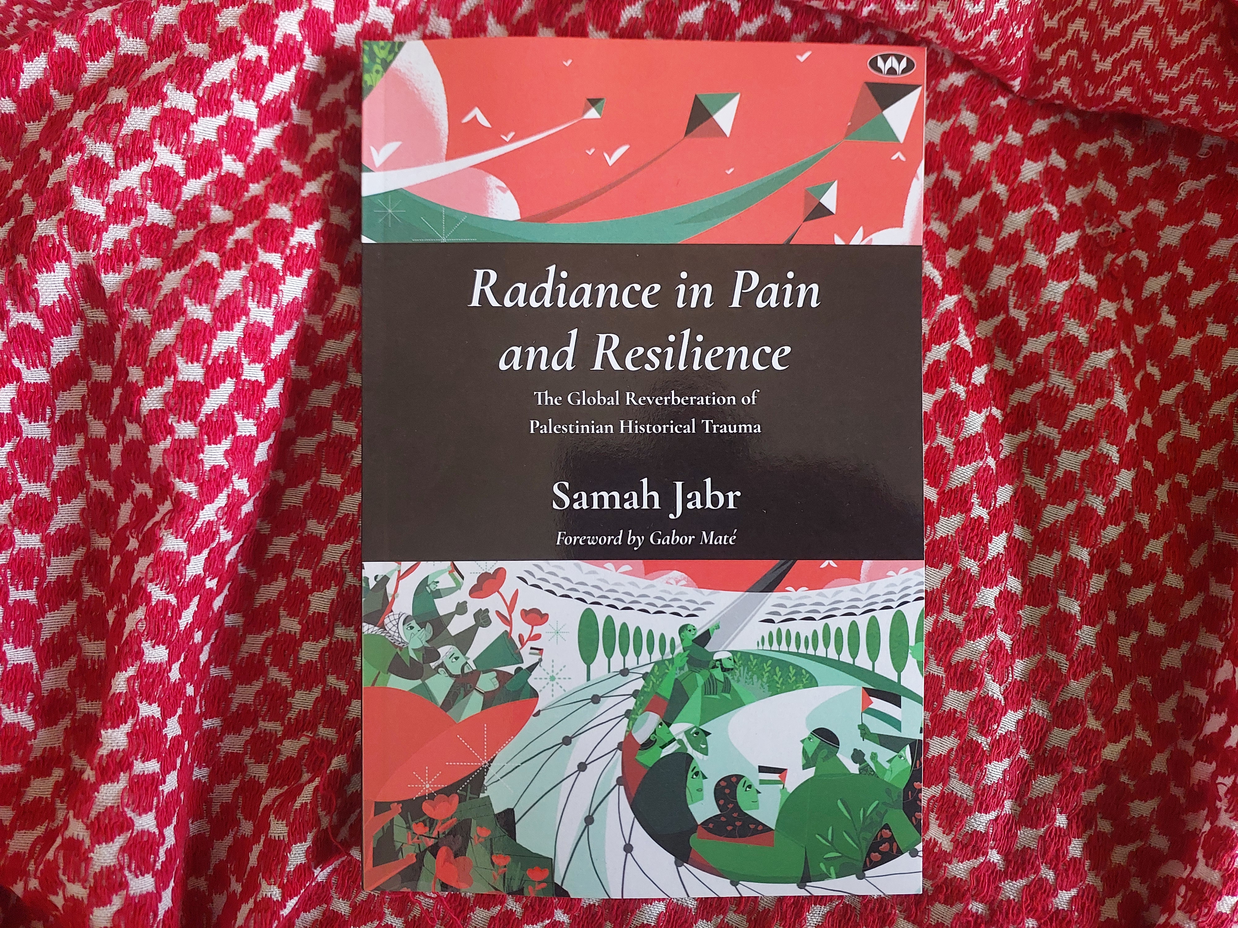 A physical copy of Radiance in Pain and Resilience: The Global Reverberation of Palestinian Historical Trauma by Dr Samah Jabr sits on top of a red and white keffiyeh