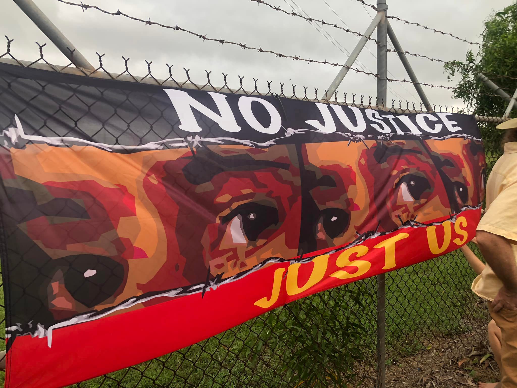 Image of a banner featuring eyes of young people locked up in prison. Text on banner reads 'no justice, just us'