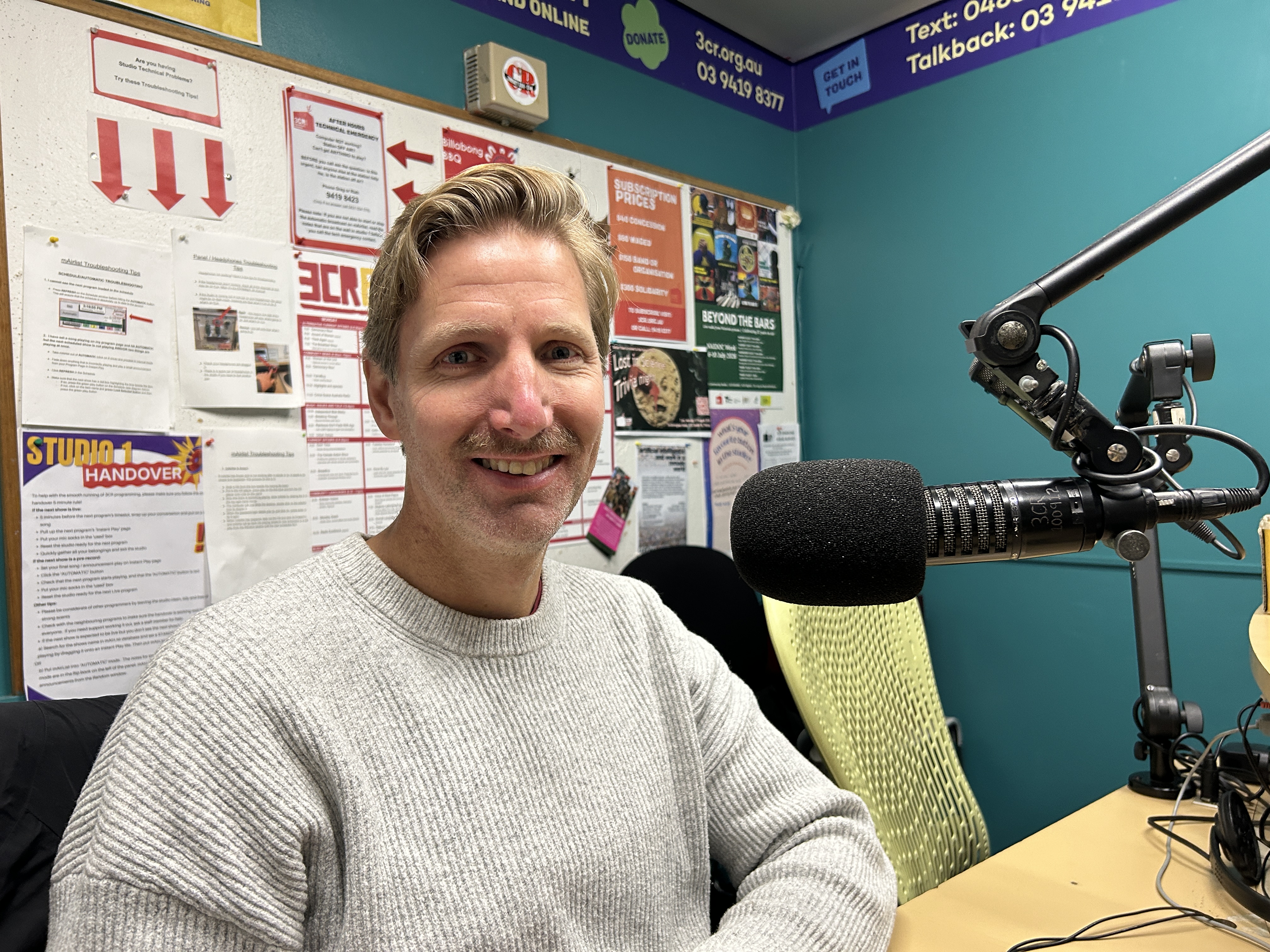 A man sits smiling in front of a microphone.