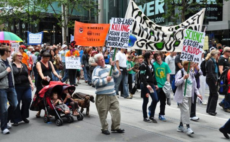 Dr Gideon Polya holding a banner at a public demonstration against climate inaction