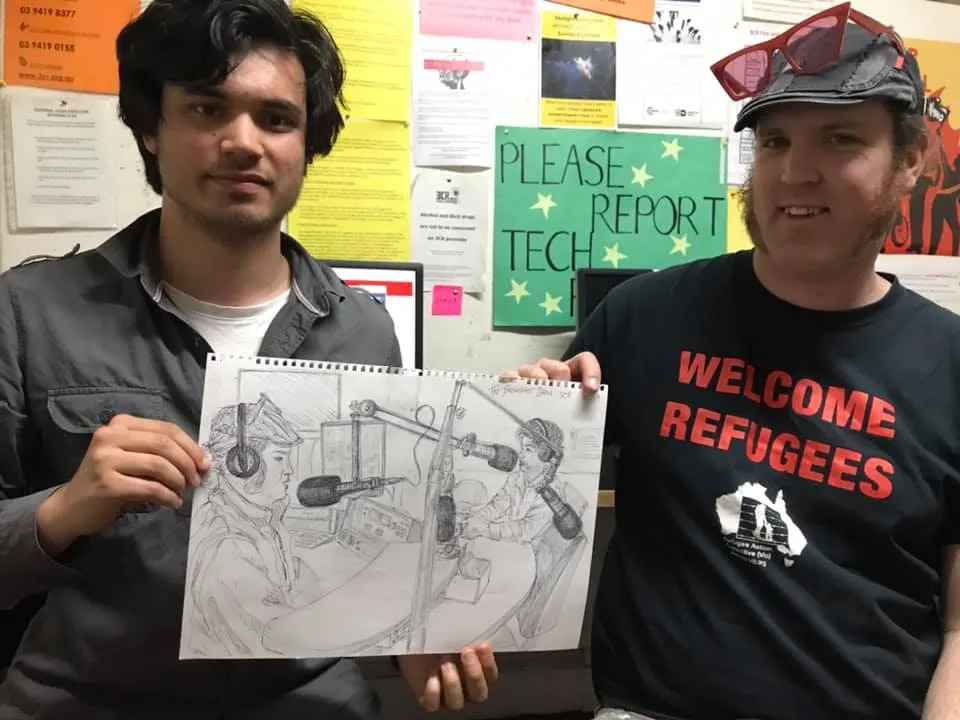 Jacob (L) and Zane Alcorn (Green Left Weekly) at 3CR holding an illustration of themselves in studio