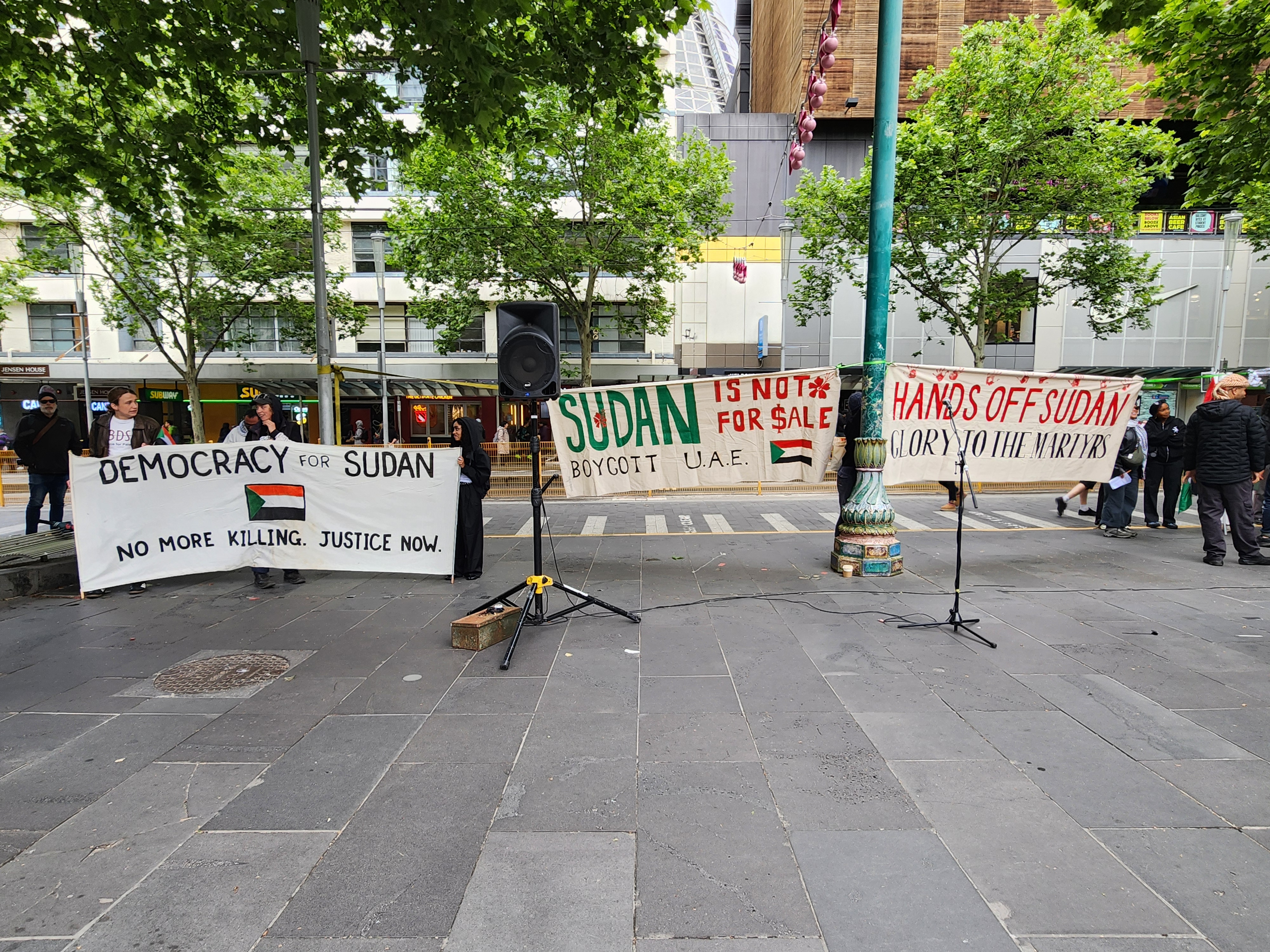 Three banners at a Rally for Sudan at the State Library that read: "Democracy for Sudan - No more killing - Justice now", "Sudan is not for sale - Boycott U.A.E." and "Hands off Sudan - glory to the martyrs"