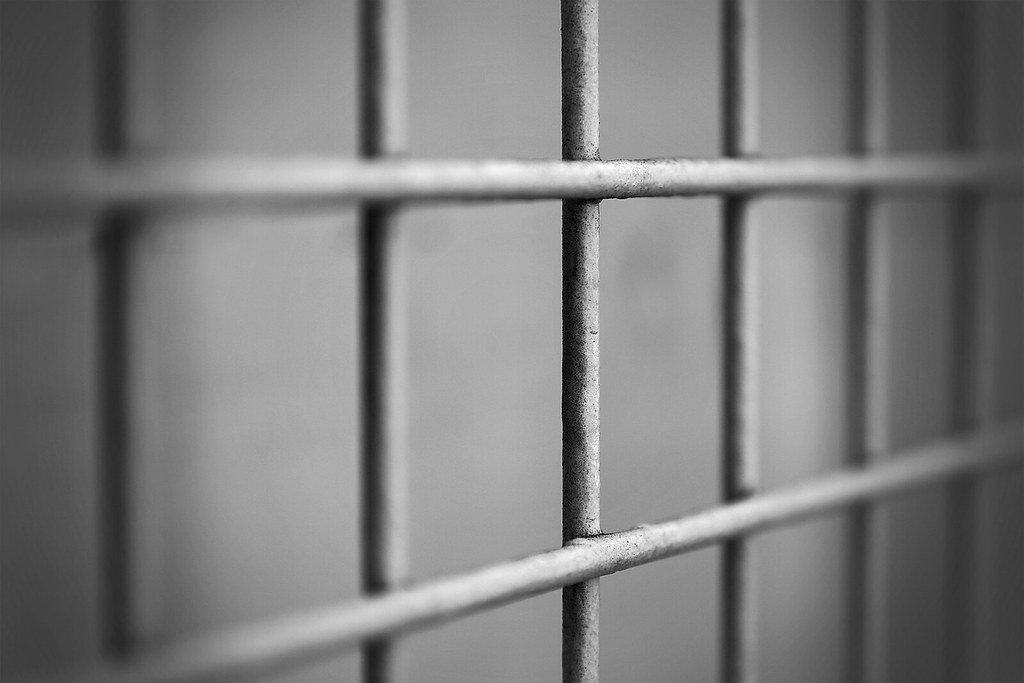 A black and white photograph of prison bars.
