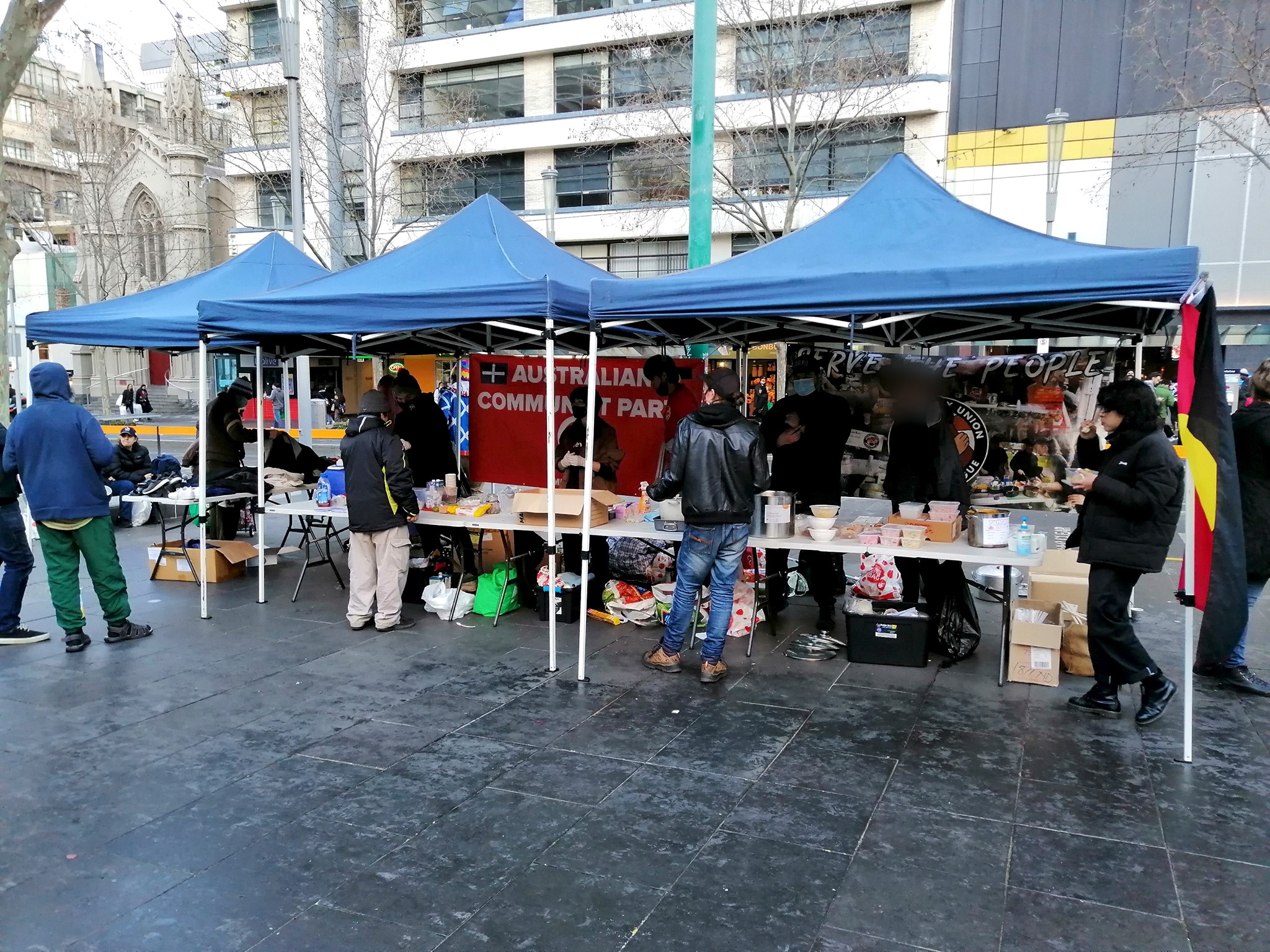 Community Union Defence League's street kitchen in the CBD- a stall under two marquees with volunteers handing out food.