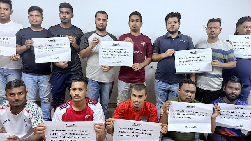 Bangladeshi migrant workers hold signs demanding Ansell take responsibility for addressing MediCeram labour violations.