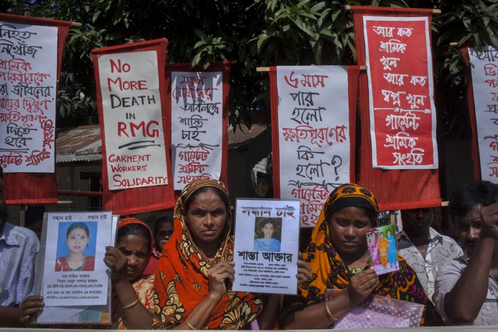 A photograph of relatives of Rana Plaza workers holding up signs in Bengali and English demanding justice in 2013.