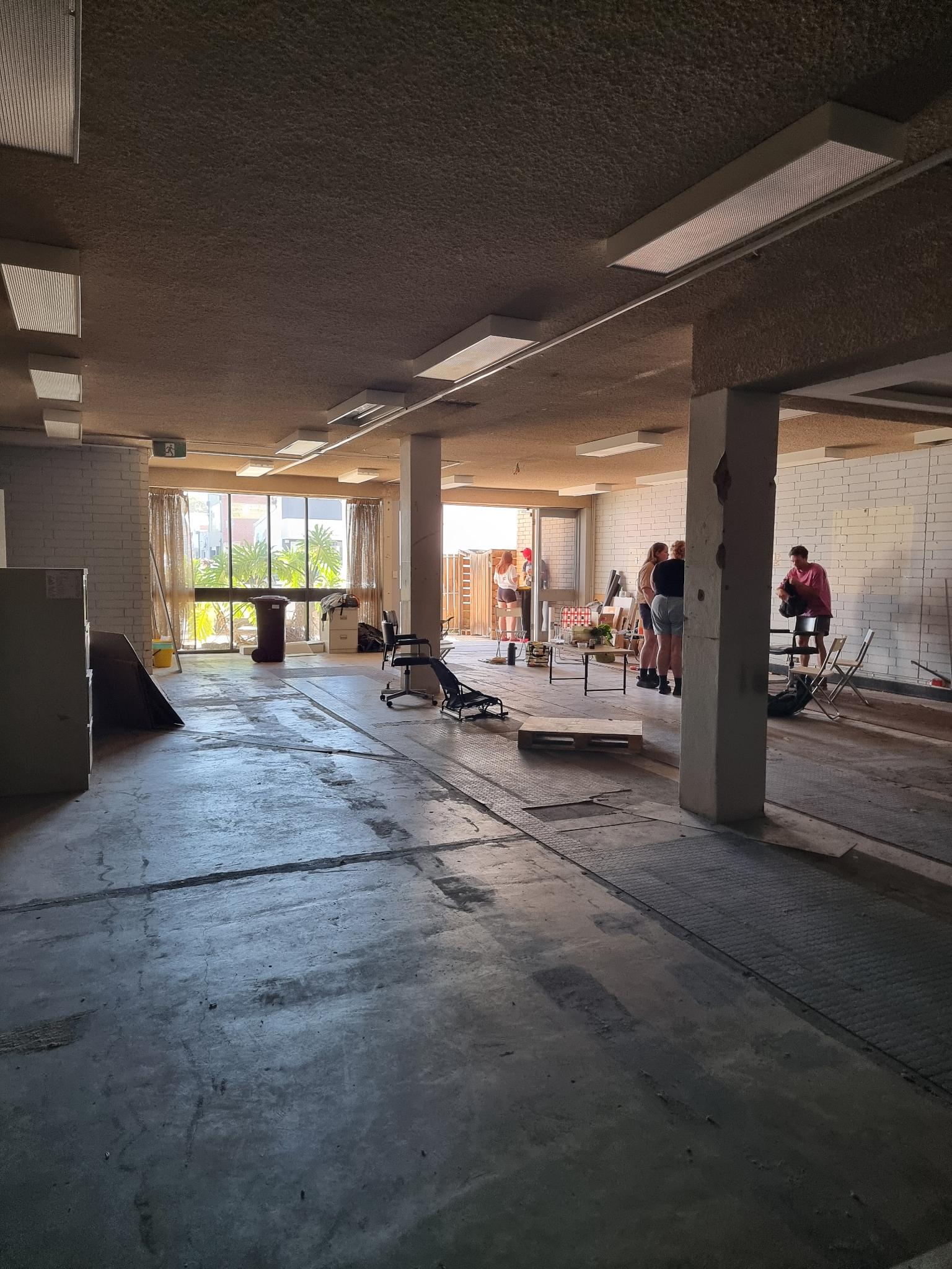 Inside the new Catalyst space, a stripped-back building interior with people doing work in the far right corner.