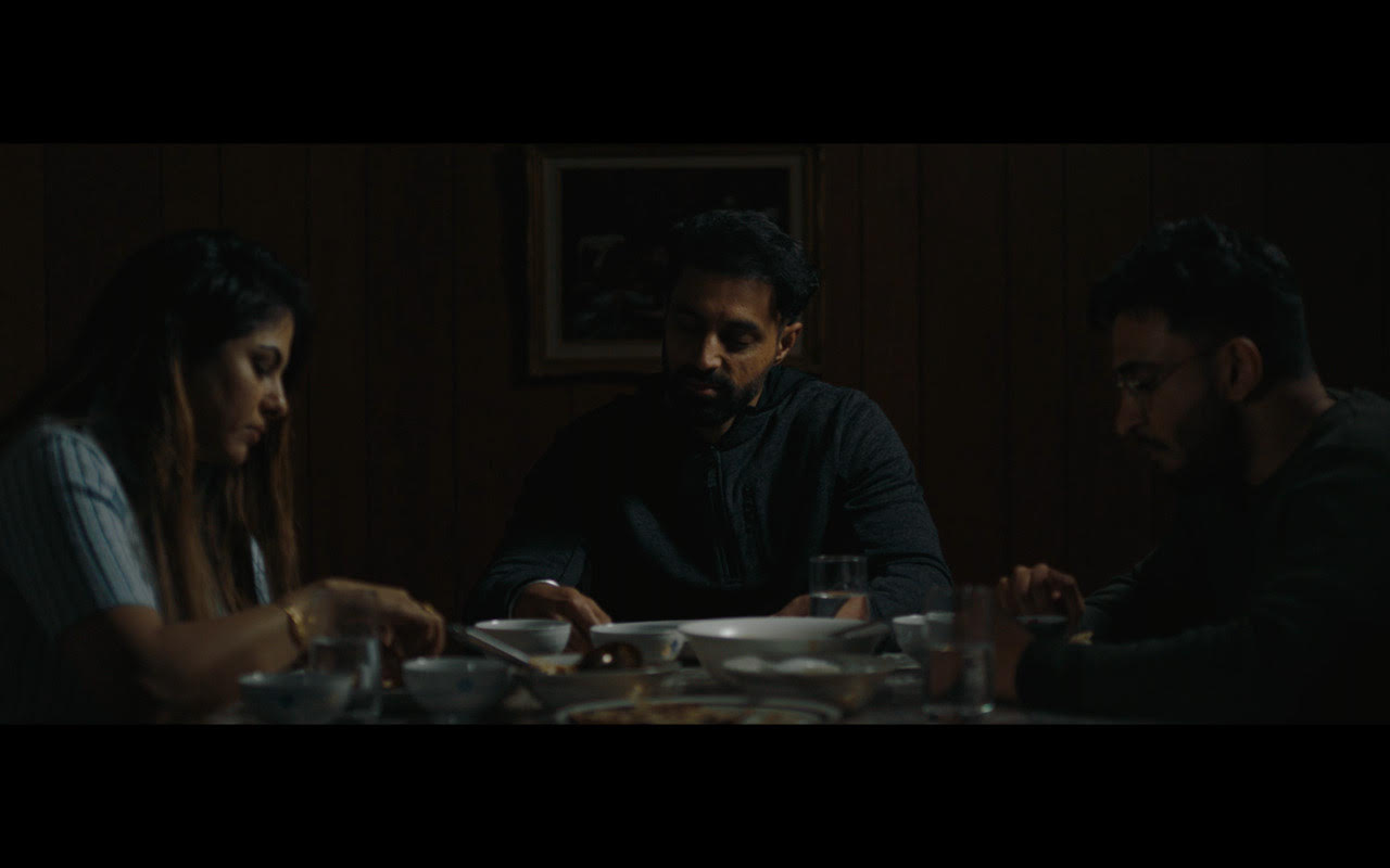 Still from Sister Mine short film. Brother, sister, and brother in law sitting at dinner table, sharing a meal. 