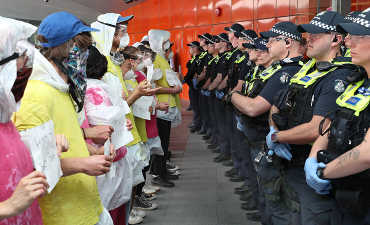 A line of protesters facing off a line of police at the IMARC blockade