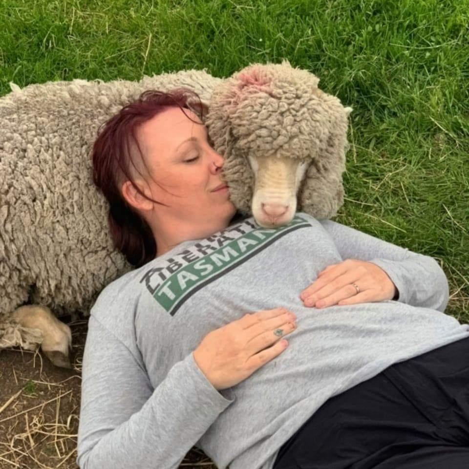 Photo of Kristy Alger reclining with a sheep