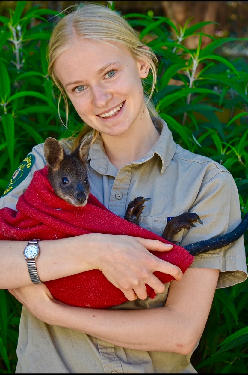  Image of Greta holding a baby joey and smiling. 