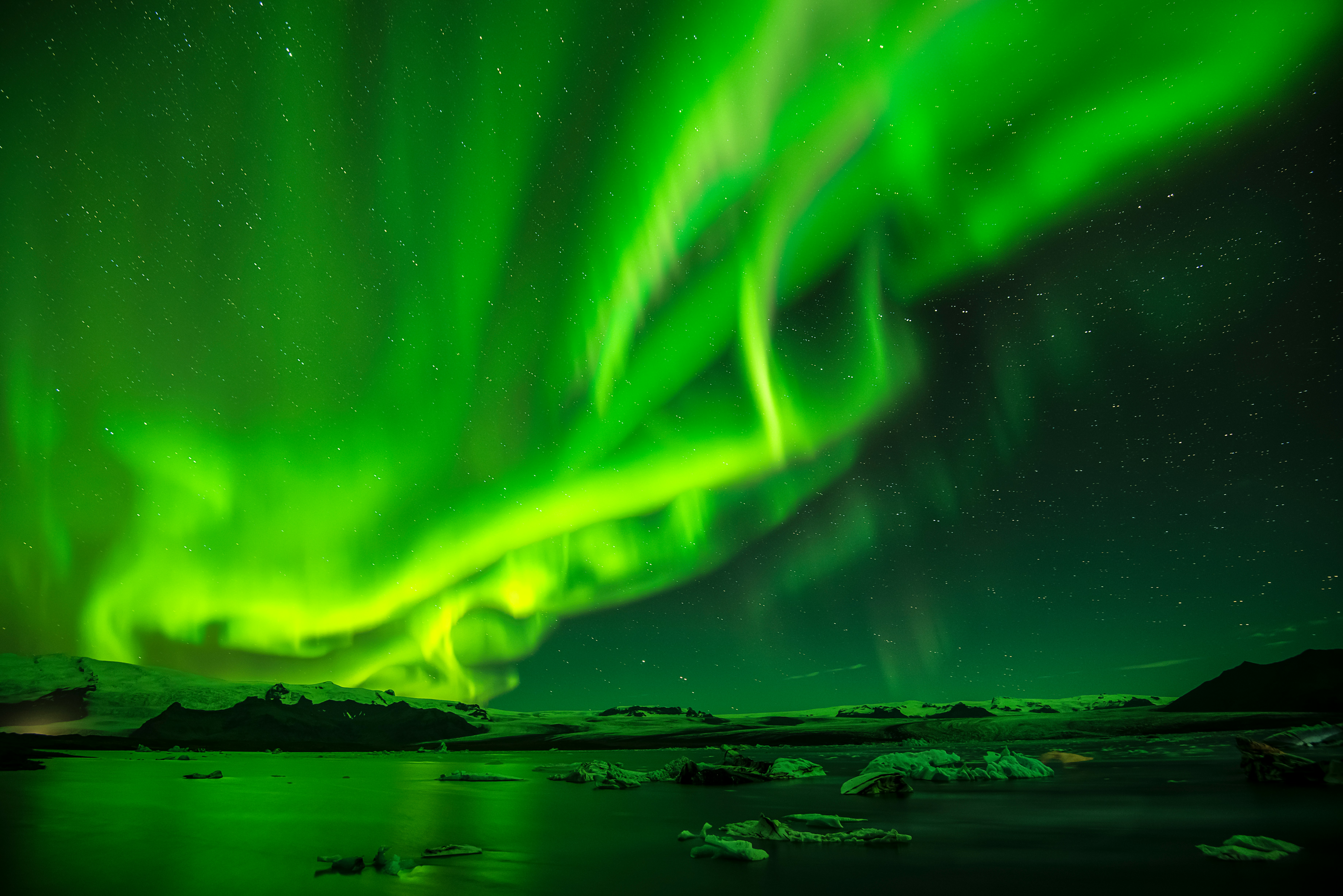 A green aurora in the sky over water.