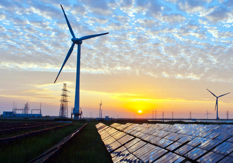 image of wind turbine and solar panels in landscape at sunset