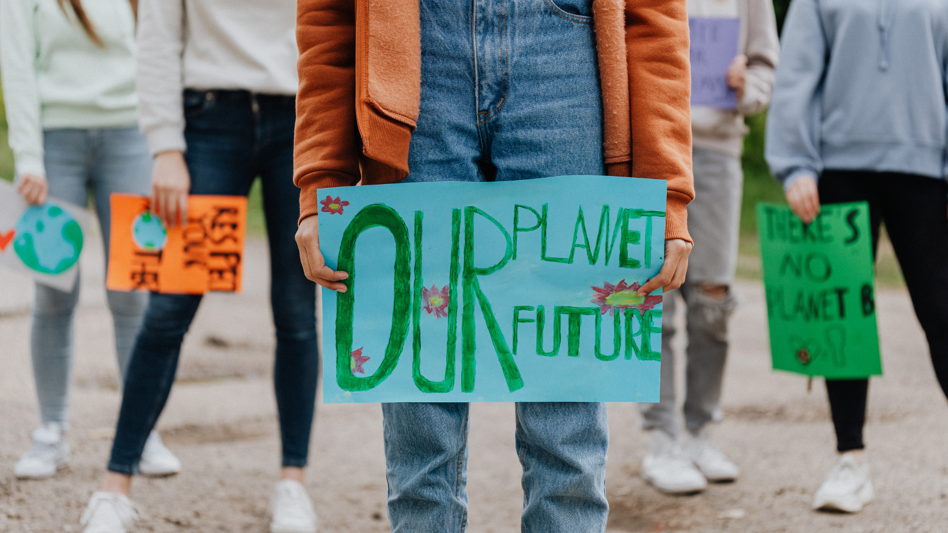 Child holding a protest sign that reads 'Our Planet, Our Future'