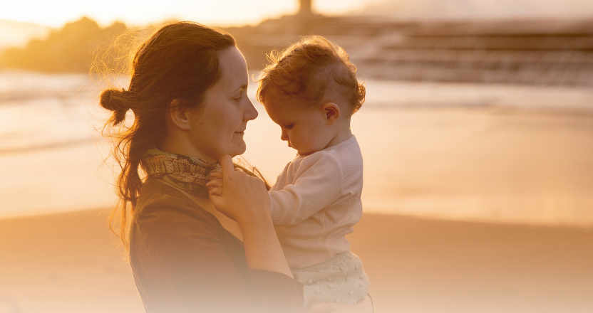Mother and child at beach in hazy light. Mother has slightly worried expression.