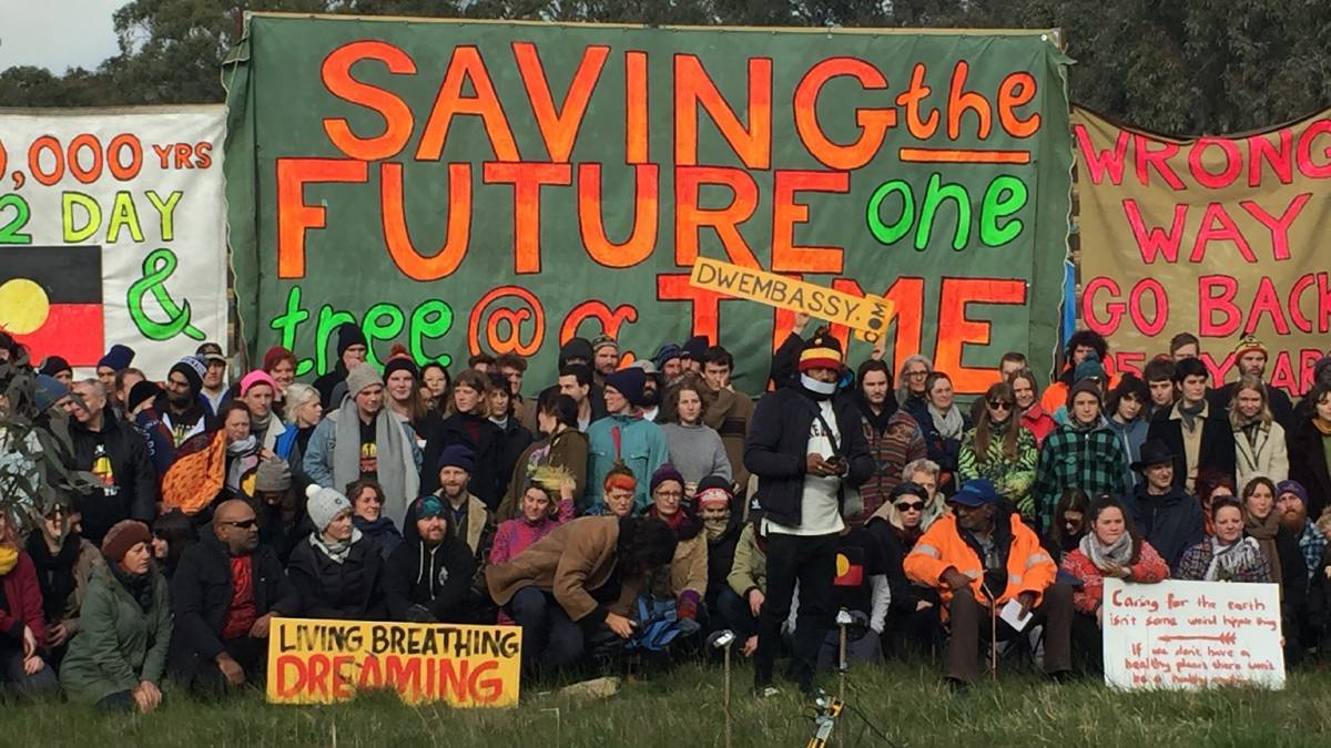 Crew gathered outside Embassy with protest banners saying saving the future one tree at a time, and other similar slogans & Aboriginal flag