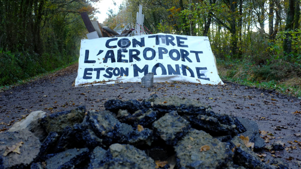 A barricade at the Notre-Dame-des-Landes ZAD. Banner reads: AGAINST THE AIRPORT AND ITS WORLD