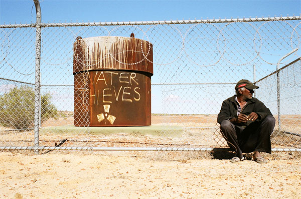 BHP Olympic Dam uranium mine fence perimeter with graffiti that says "water thieves"