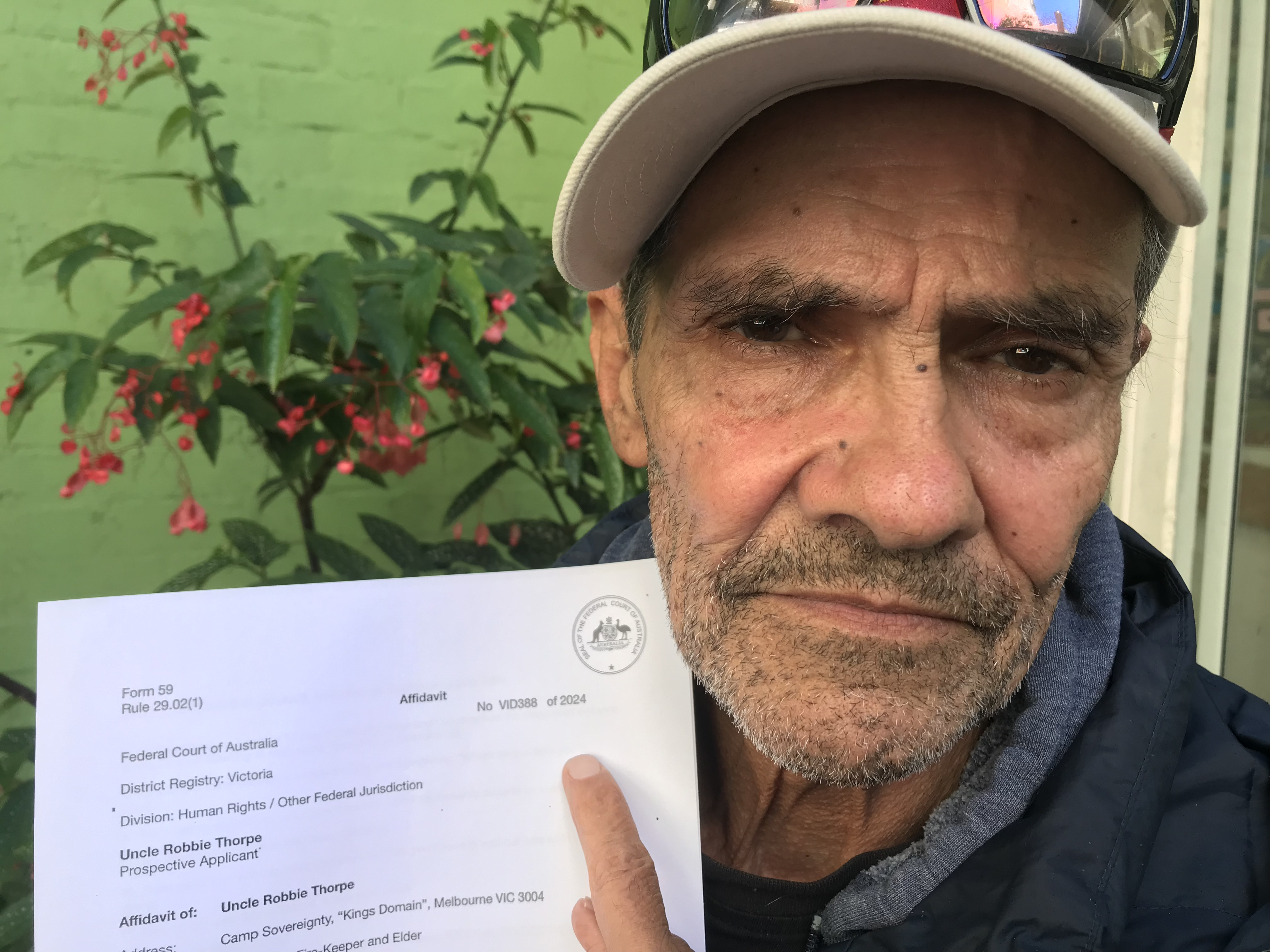 Djuran Bunjileenee Robbie Thorpe holding an affidavit in the 3CR garden