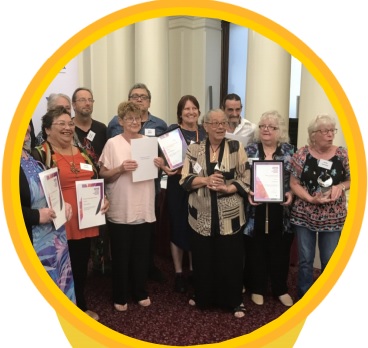A group of older people holding up certificates they have been awarded