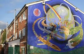 A large house with a mural painted on the side depicting the earth with a group of people riding around it on rockets