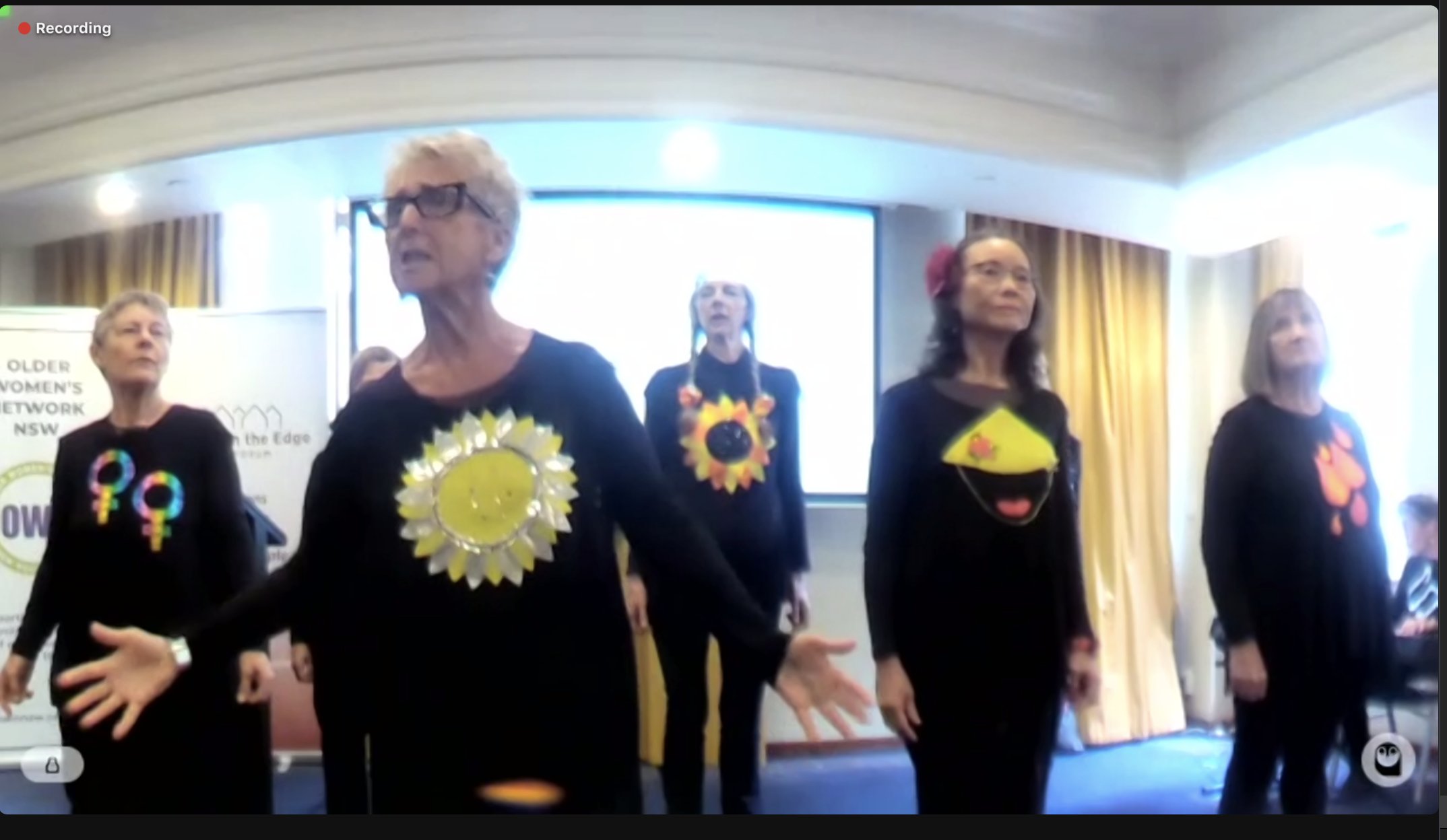 A group of five older women singing as a group