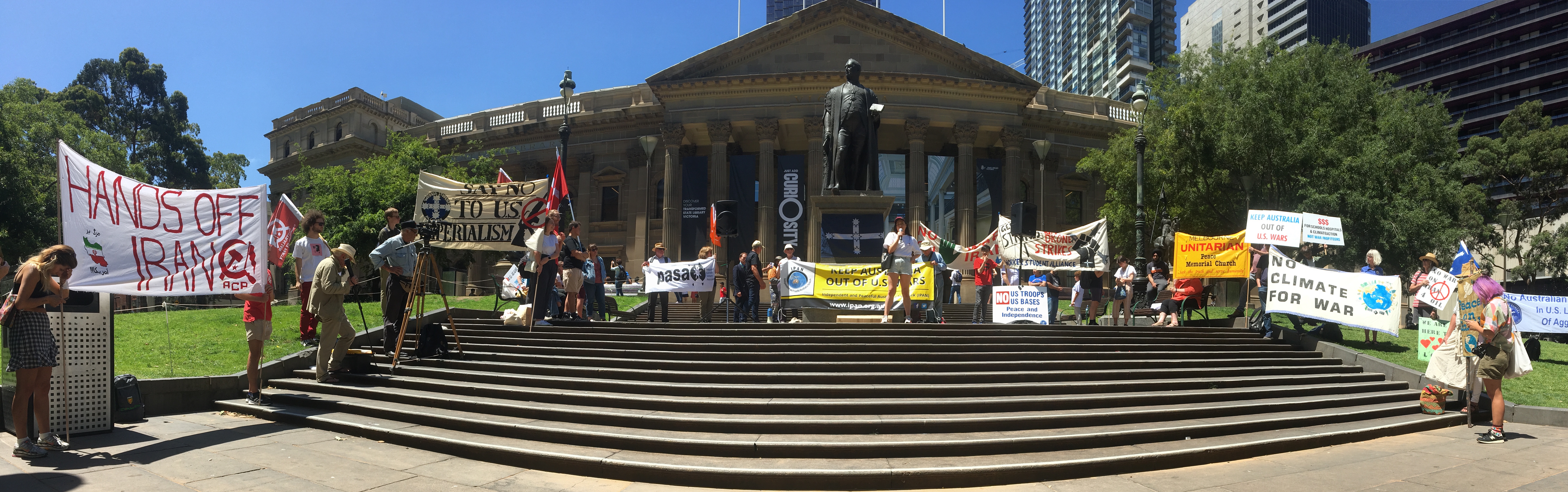 Activists with banners gather for speeches on the steps of the State Library of Victoria as part of a global day of action calling for 'No War with Iran'