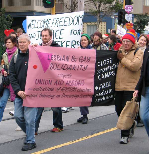 Marchers at a pro-refugee protest in Melbourne 2004. Two carry a banner reading Lesbian and Gay Solidarity, Close the Concentration Camps.