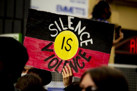 A hand-painted placard at the rally features the Aboriginal flag with the words 'Silence is Violence'. Photograph by Brendan Bonsack.