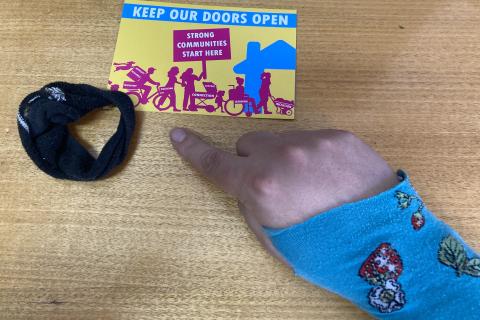 Image of the Neighbourhood Housing Postcard with a hair tie and glove made from socks