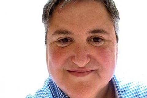 heahshot of Tony Briffa Grey/black hair blue shirt