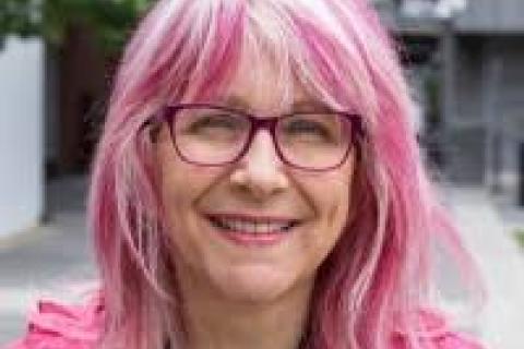 femme appearing person pink hair dark-rimmed glasses