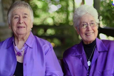 two older women both with gret\ying hair and wearing purple tops