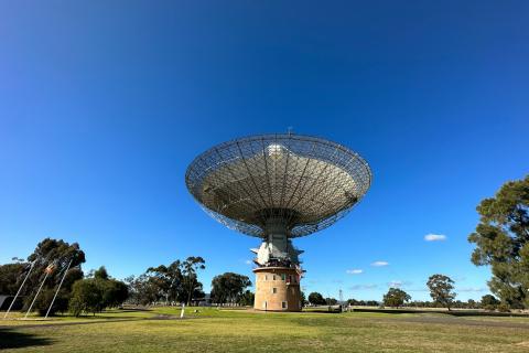 Radio telescope dish pointed upward at blue sky