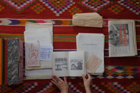 Image of archival documents and illustrations from feminist organisations and associations in Algeria. The black and white documents are set against a brightly coloured geometric table cloth.
