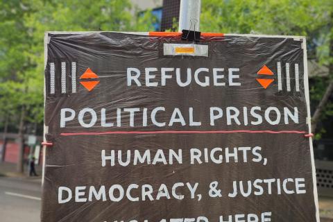 'Refugee Political Prison, Human Rights, Democracy & Justice Violated here' placard on a pole in front of refugee hotel prison in Melbourne.