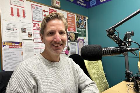 A man sits smiling in front of a microphone.