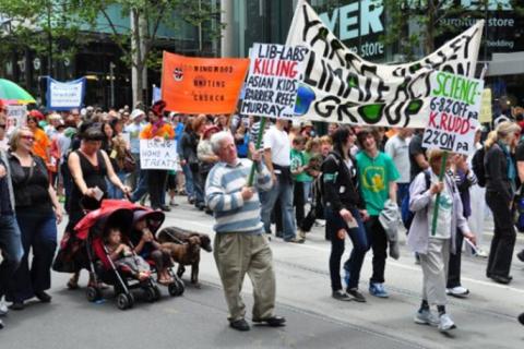 Dr Gideon Polya holding a banner at a public demonstration against climate inaction