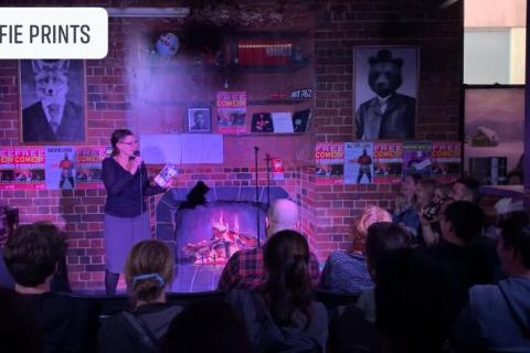 A comedian stands in front of a packed crowd. 