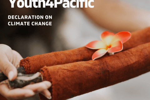 A photograph of two hands holding a brown scroll with a pink and yellow frangipani flower placed on top of it. In the top right in white lettering is written "Youth4Pacific Declaration on Climate Change.