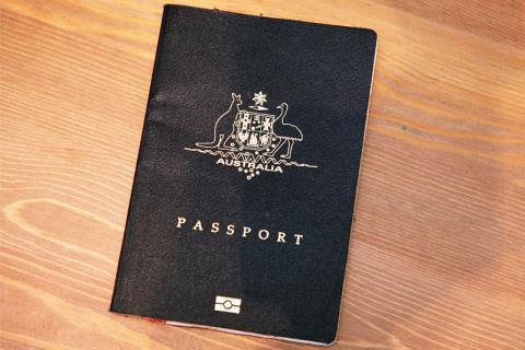 Blue/Black Australian Passport Against Brown Wooden Table. 